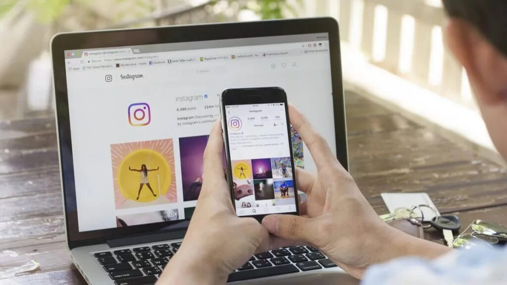 An Instagrammer uses a computer and a phone to view Instagram