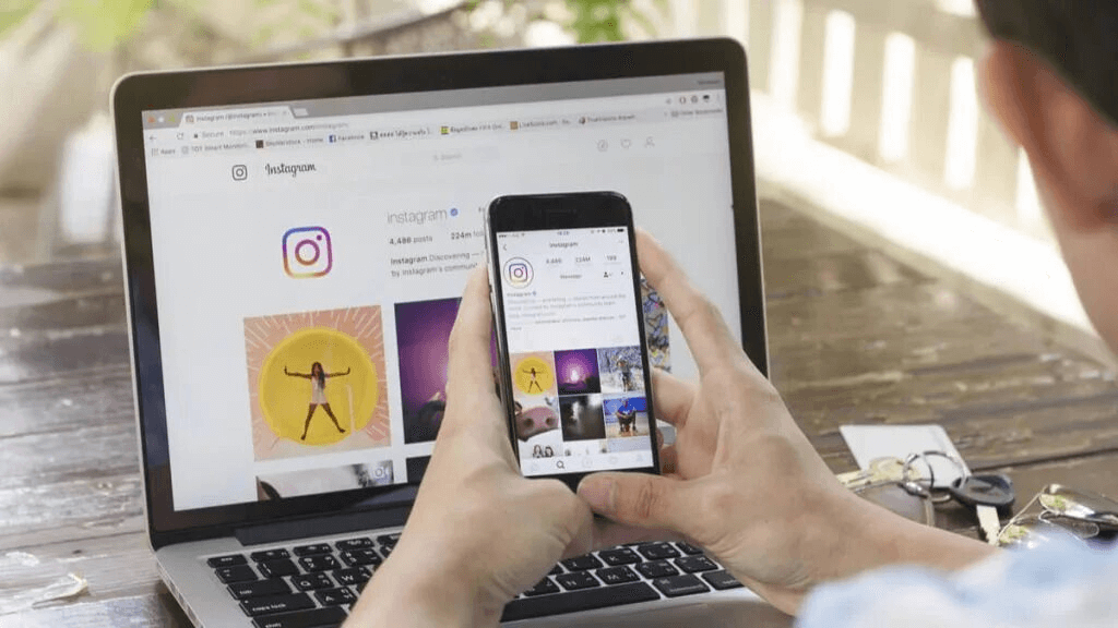 Một người dùng Instagram sử dụng máy tính và điện thoại để kiểm tra Instagram.